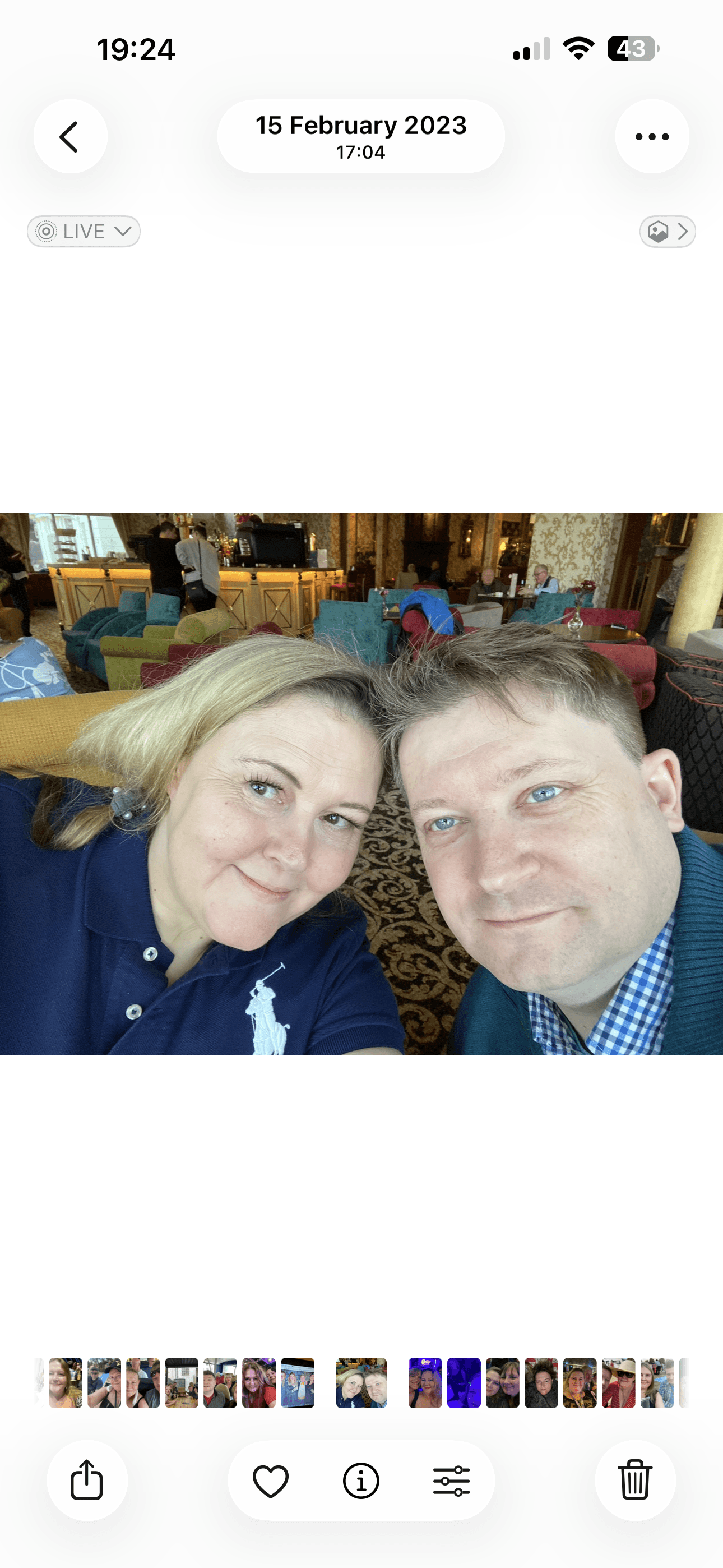 A smiling man and woman take a close-up selfie in a lounge with colorful furniture.